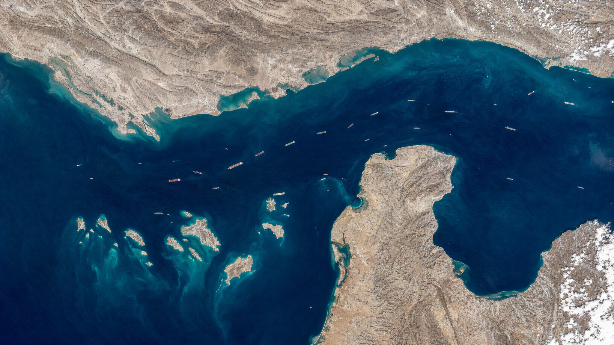 Aerial view of the Strait of Hormuz — the 21-mile-wide waterway between Iran and Oman through which 21% of the world's oil supply passes every day.
