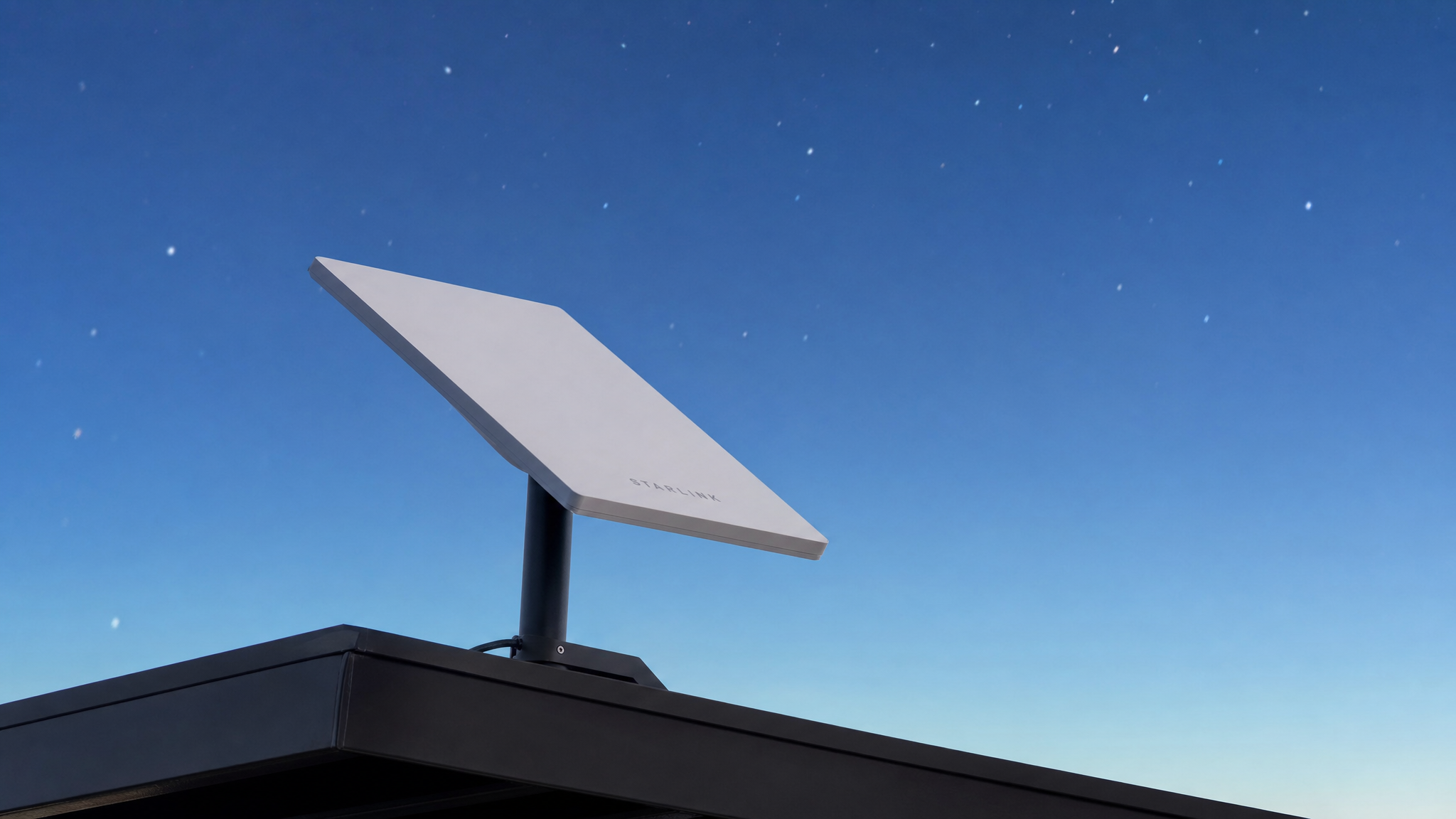 A Starlink satellite internet dish — flat, white, pizza-box sized — mounted and pointing at the sky. Delivers 100–200 Mbps of fiber-competitive internet anywhere on Earth, no cable or ground infrastructure required.
